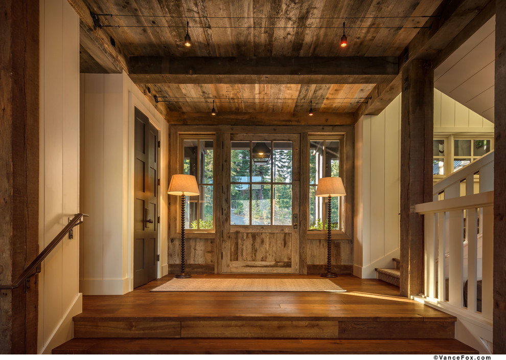 Imagen de puerta principal rústica grande con paredes blancas, suelo de madera en tonos medios, puerta simple y puerta de madera en tonos medios