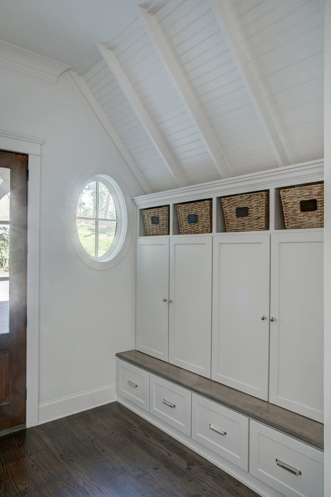 Idée de décoration pour une entrée chalet de taille moyenne avec un vestiaire, un mur blanc, parquet foncé, une porte simple, une porte en bois foncé et un sol marron.