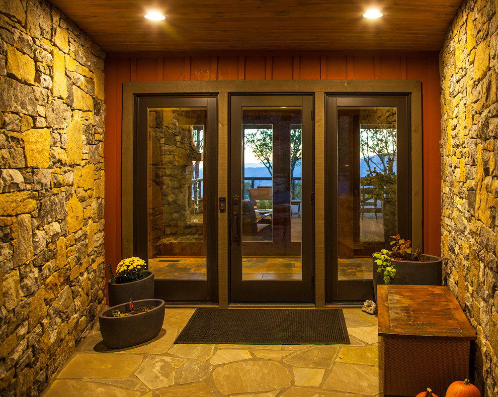 他の地域にある高級な広いコンテンポラリースタイルのおしゃれな玄関ラウンジ (茶色い壁、スレートの床、濃色木目調のドア、マルチカラーの床) の写真