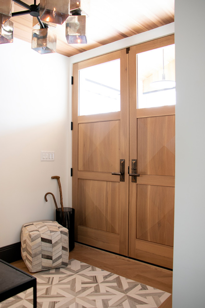 Immagine di un piccolo ingresso minimalista con pareti bianche, pavimento in marmo, una porta a due ante, una porta in legno chiaro e pavimento bianco