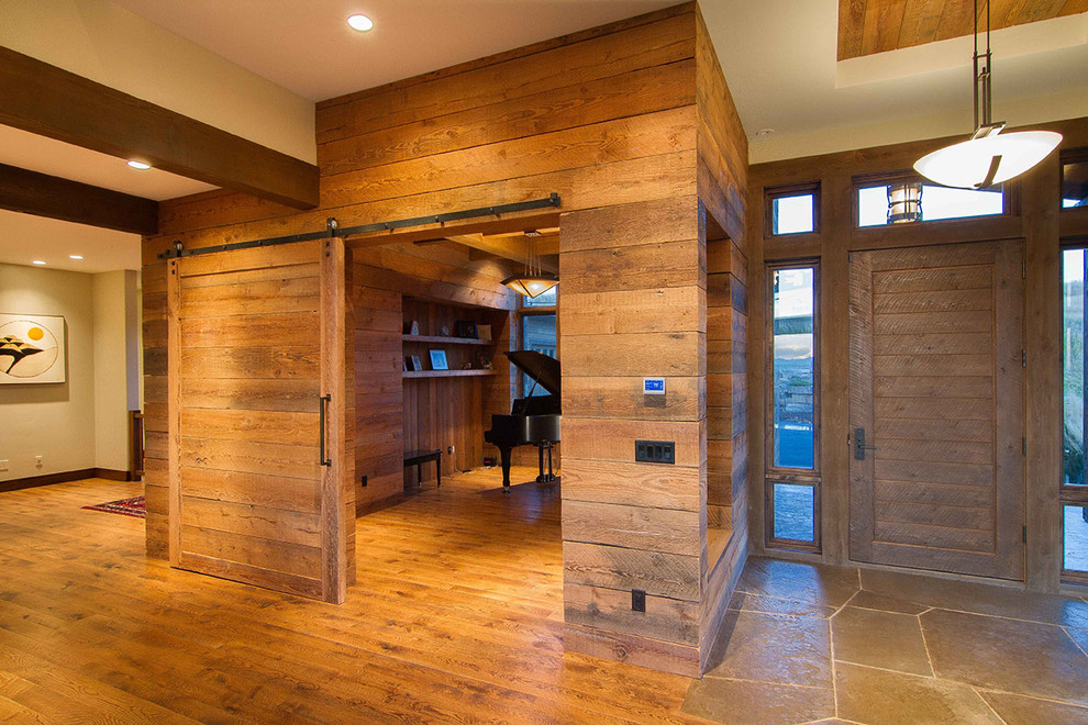 Ejemplo de distribuidor rústico grande con paredes marrones, suelo de madera clara, puerta simple y puerta de madera clara