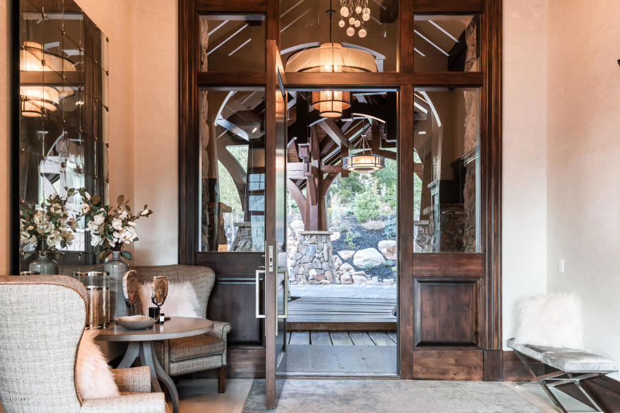 На фото: огромная входная дверь в стиле неоклассика (современная классика) с коричневыми стенами, паркетным полом среднего тона, одностворчатой входной дверью, входной дверью из темного дерева и коричневым полом