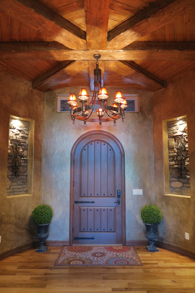 На фото: большое фойе в средиземноморском стиле с паркетным полом среднего тона, одностворчатой входной дверью и коричневой входной дверью