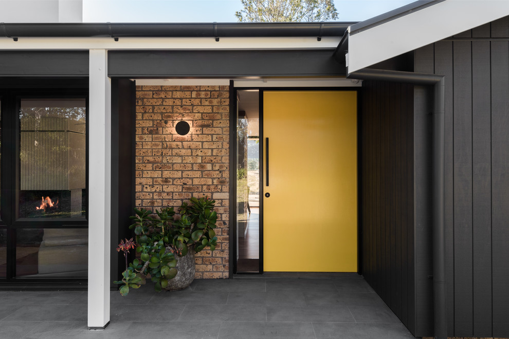 На фото: входная дверь среднего размера в стиле ретро с серыми стенами, полом из сланца, одностворчатой входной дверью, желтой входной дверью и серым полом с