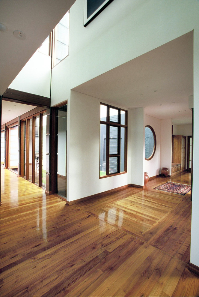 Aménagement d'un très grand hall d'entrée asiatique avec un mur blanc, un sol en bois brun, une porte double et un sol marron.