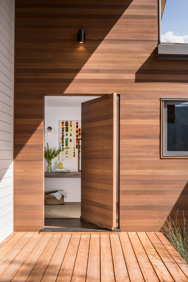 Exemple d'une porte d'entrée tendance avec une porte en bois brun et une porte pivot.