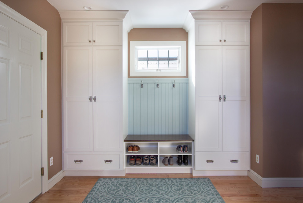 Example of a small transitional medium tone wood floor and blue floor mudroom design in New York with brown walls and a white front door