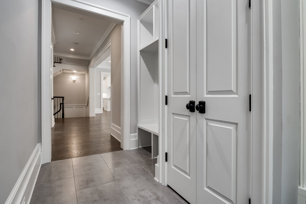 Idées déco pour une entrée classique de taille moyenne avec un vestiaire, un mur gris, un sol en bois brun, une porte simple, une porte blanche et un sol gris.