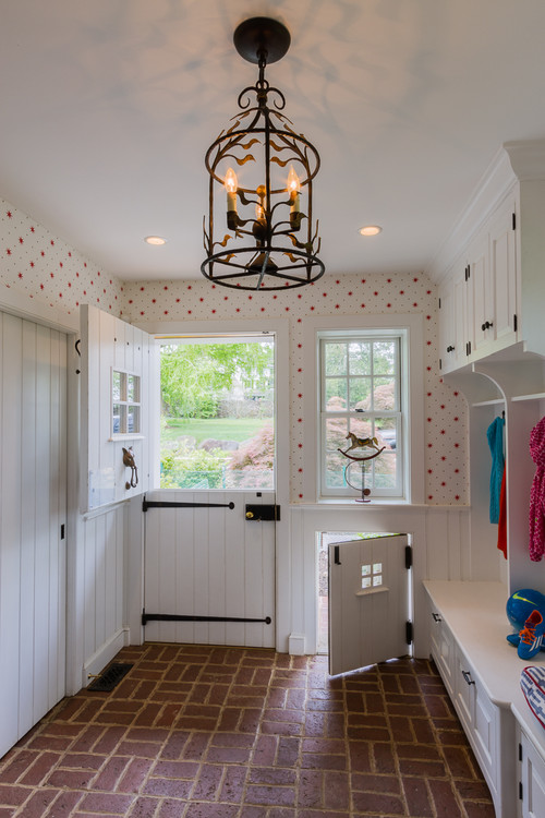 The main entrance to the mudroom features a classic Dutch door with vertical wood slats and a four-pane window. Just beside it, under a window, is a custom dog door that echoes the same design—only in miniature.
