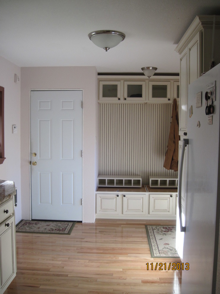 Cette image montre une entrée rustique de taille moyenne avec un vestiaire, un mur rose, parquet clair, une porte simple et une porte blanche.