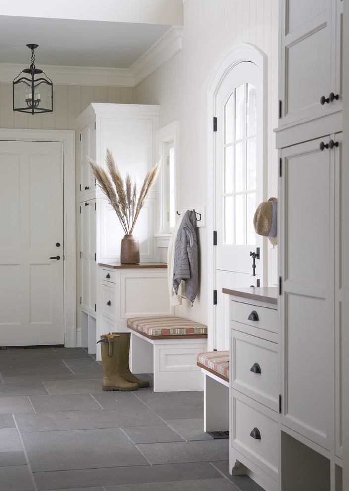 This is an example of a large rural boot room in New York with white walls, slate flooring, a stable front door, a white front door and grey floors.