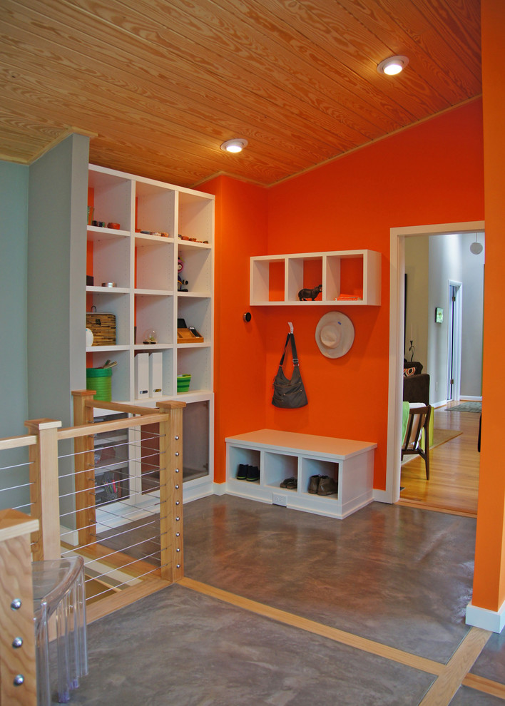 Inspiration för moderna kapprum, med orange väggar och betonggolv