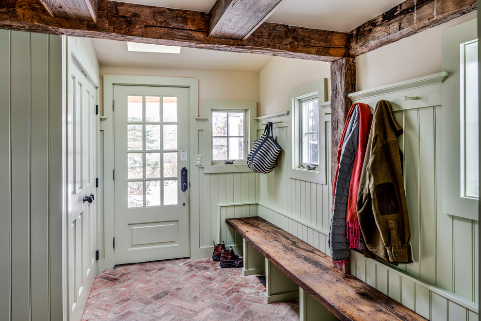 Inredning av ett klassiskt kapprum, med gröna väggar, tegelgolv, en enkeldörr och en grön dörr