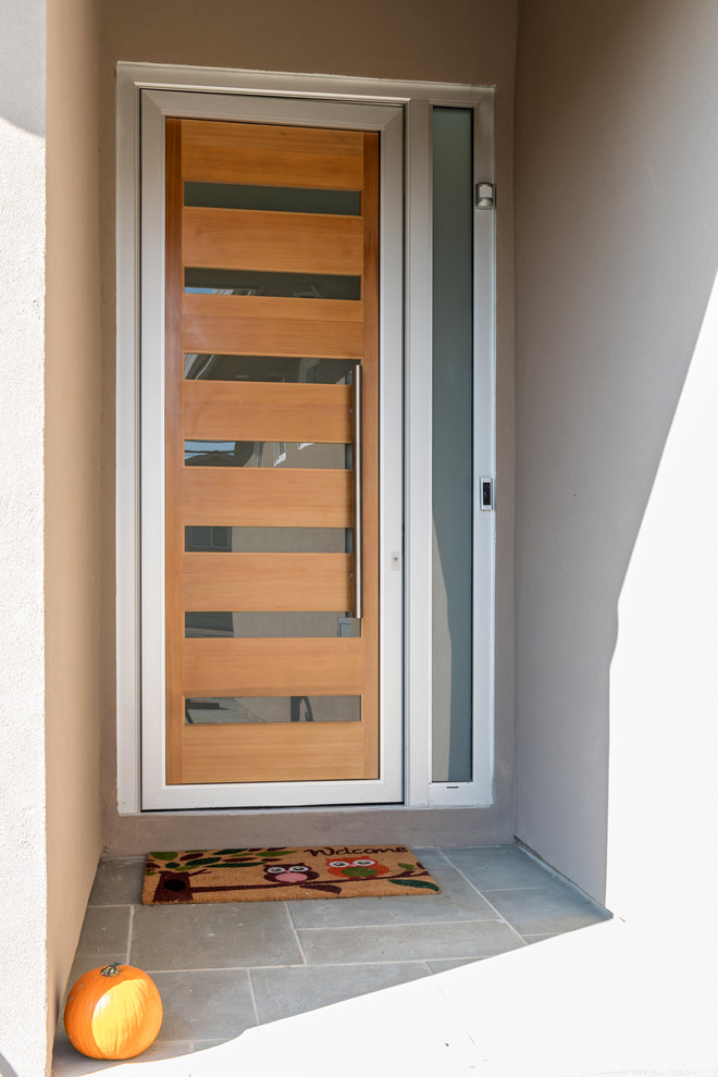 На фото: маленькая входная дверь в современном стиле с бежевыми стенами, одностворчатой входной дверью, входной дверью из светлого дерева и серым полом для на участке и в саду с