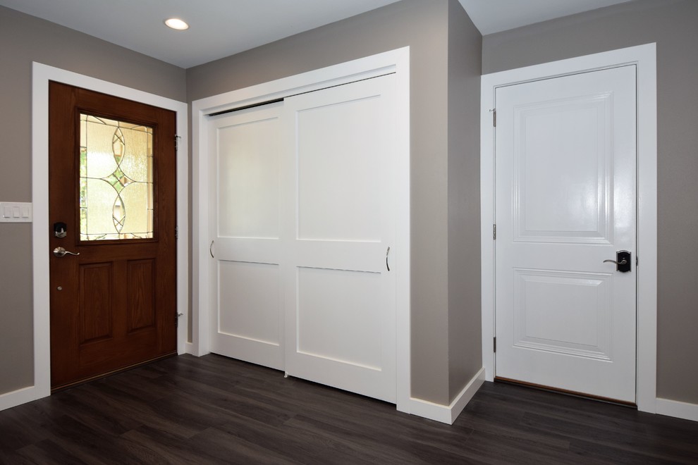 Foto di un ingresso tradizionale di medie dimensioni con pareti beige, pavimento in laminato, una porta singola, una porta in legno bruno e pavimento marrone