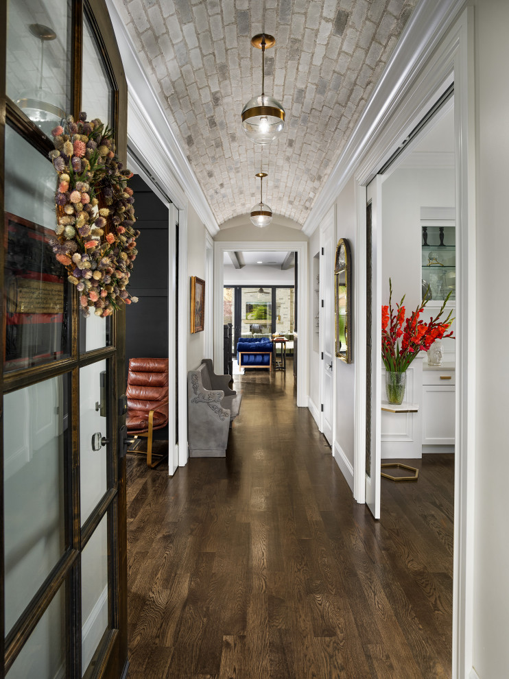 Aménagement d'une entrée classique avec un couloir, un mur gris, parquet foncé, une porte simple, une porte en verre, un sol marron et un plafond voûté.