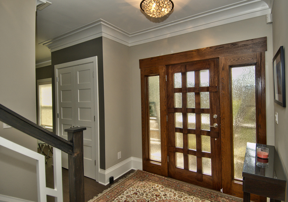Imagen de distribuidor clásico renovado de tamaño medio con paredes grises, suelo de madera oscura, puerta simple y puerta de madera en tonos medios