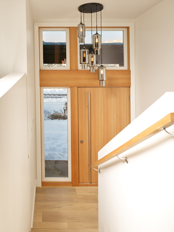 Immagine di una porta d'ingresso moderna di medie dimensioni con pareti bianche, parquet chiaro, una porta singola, una porta in legno chiaro e pavimento marrone