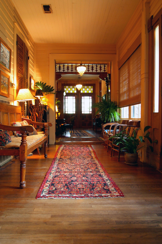 Foto di un corridoio american style con pavimento in legno massello medio, una porta a due ante e una porta in legno scuro
