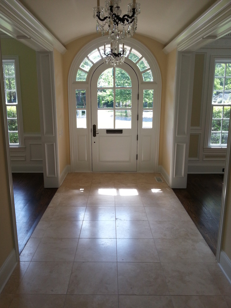 Entryway - large traditional medium tone wood floor entryway idea in Charlotte with yellow walls and a white front door