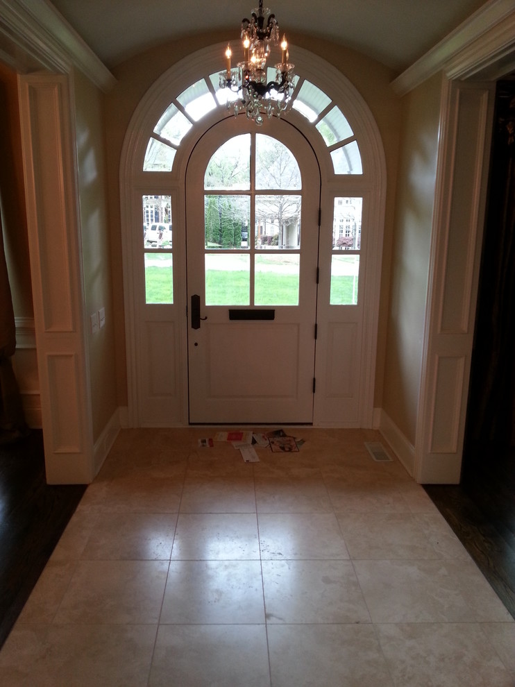 Example of a large classic medium tone wood floor entryway design in Charlotte with yellow walls and a white front door