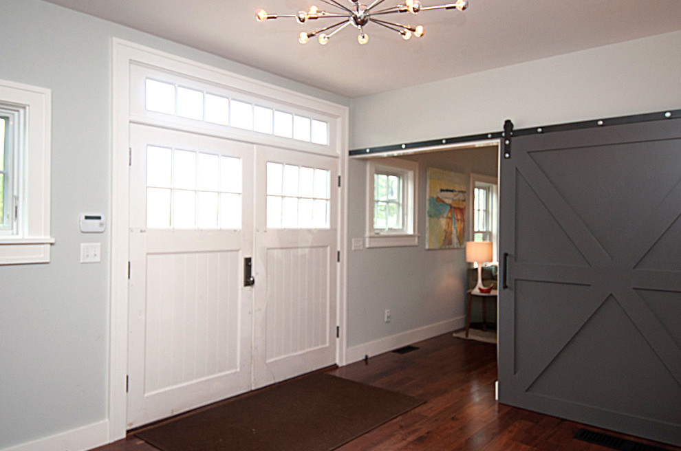 На фото: фойе среднего размера в стиле неоклассика (современная классика) с серыми стенами, темным паркетным полом, двустворчатой входной дверью и белой входной дверью с