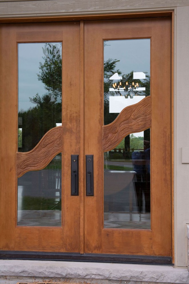 Cette image montre une grande porte d'entrée chalet avec une porte double et une porte en bois brun.