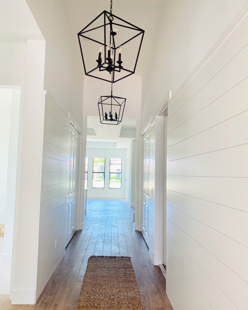 Inspiration for a coastal brown floor and shiplap wall entryway remodel in Miami with white walls