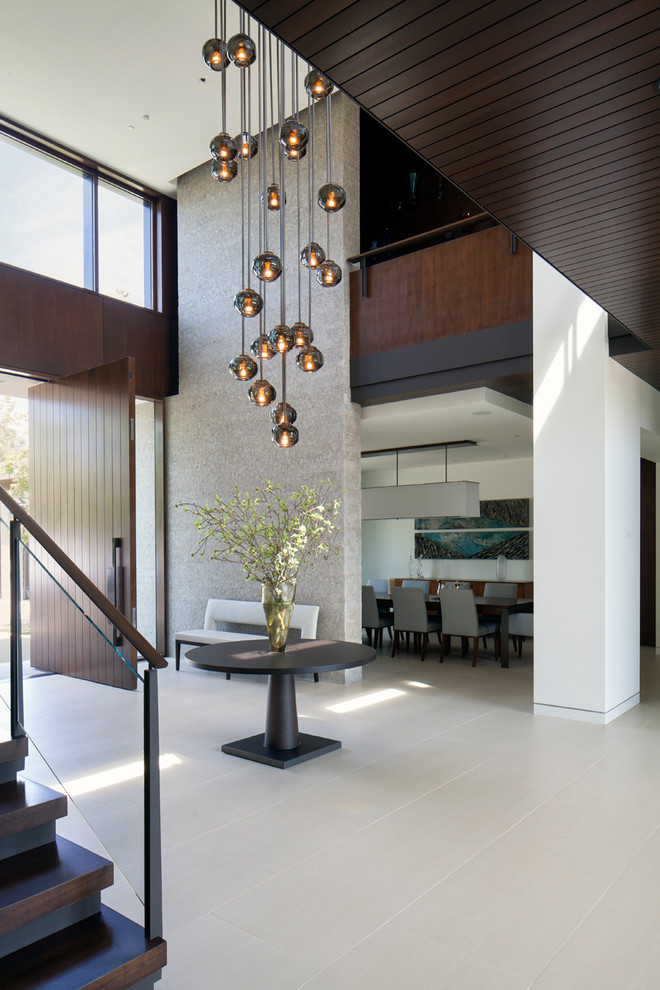Geräumiges Modernes Foyer mit weißer Wandfarbe, Porzellan-Bodenfliesen, Drehtür, dunkler Holzhaustür und grauem Boden in Los Angeles