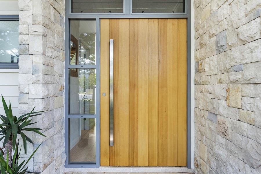 Ispirazione per una porta d'ingresso costiera di medie dimensioni con pareti bianche, una porta a pivot e una porta in legno chiaro