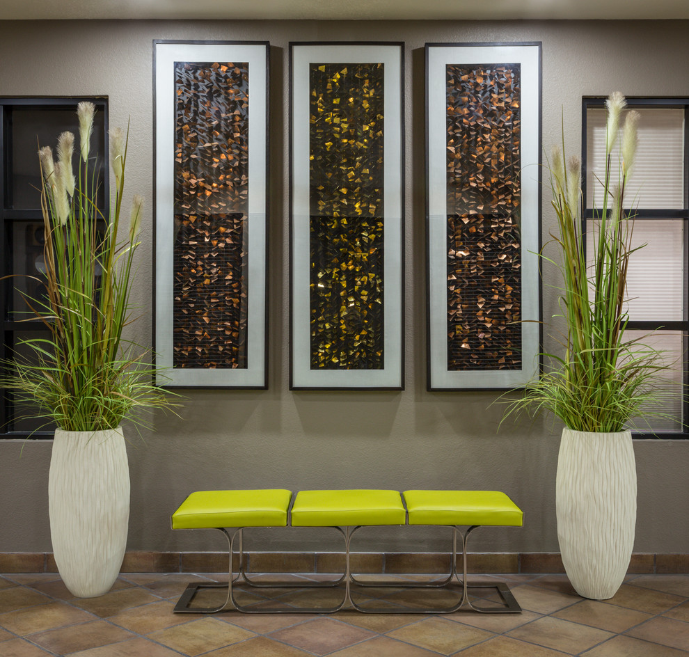 Idée de décoration pour un grand hall d'entrée minimaliste avec un mur beige et tomettes au sol.