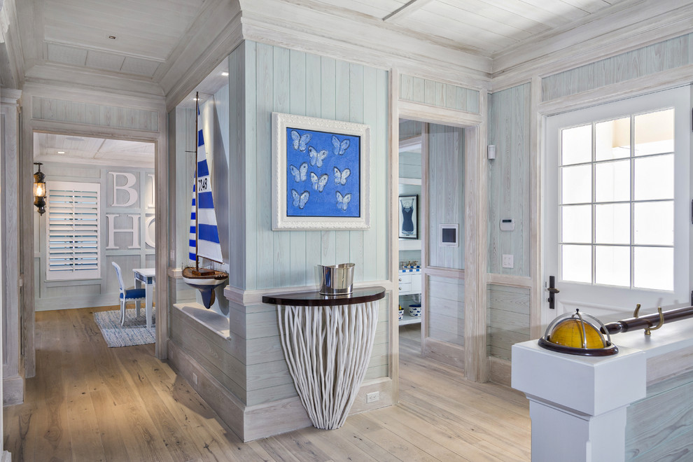 Example of a mid-sized beach style light wood floor entryway design in Miami with blue walls and a white front door