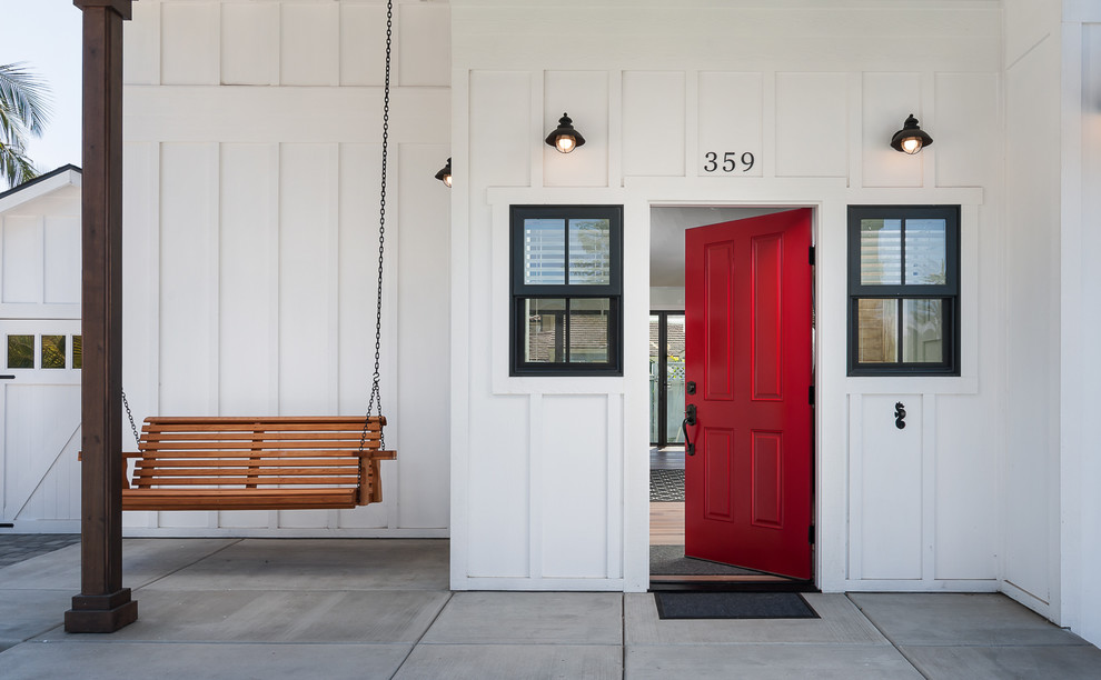 Immagine di una porta d'ingresso country di medie dimensioni con pareti bianche, pavimento in legno massello medio, una porta singola, una porta rossa e pavimento marrone
