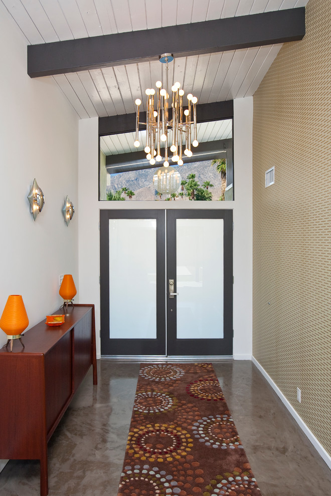 Photo of a large retro front door in Other with white walls, concrete flooring, a double front door and a dark wood front door.
