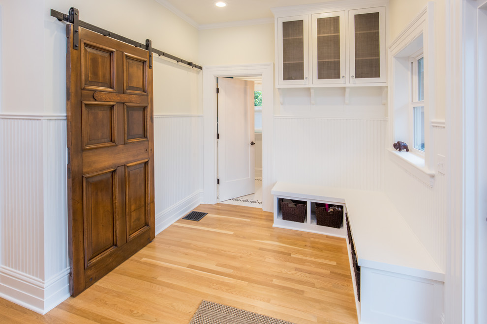 Idées déco pour une entrée craftsman de taille moyenne avec un vestiaire, un mur blanc, parquet clair, une porte en bois foncé et un sol beige.