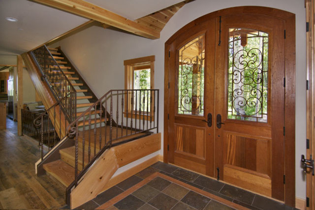 Cette image montre un hall d'entrée chalet de taille moyenne avec un mur blanc, un sol en ardoise, une porte double et une porte en bois clair.