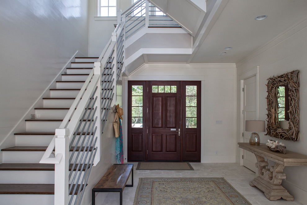 Modelo de puerta principal costera de tamaño medio con paredes blancas, suelo de travertino, puerta simple y puerta de madera oscura