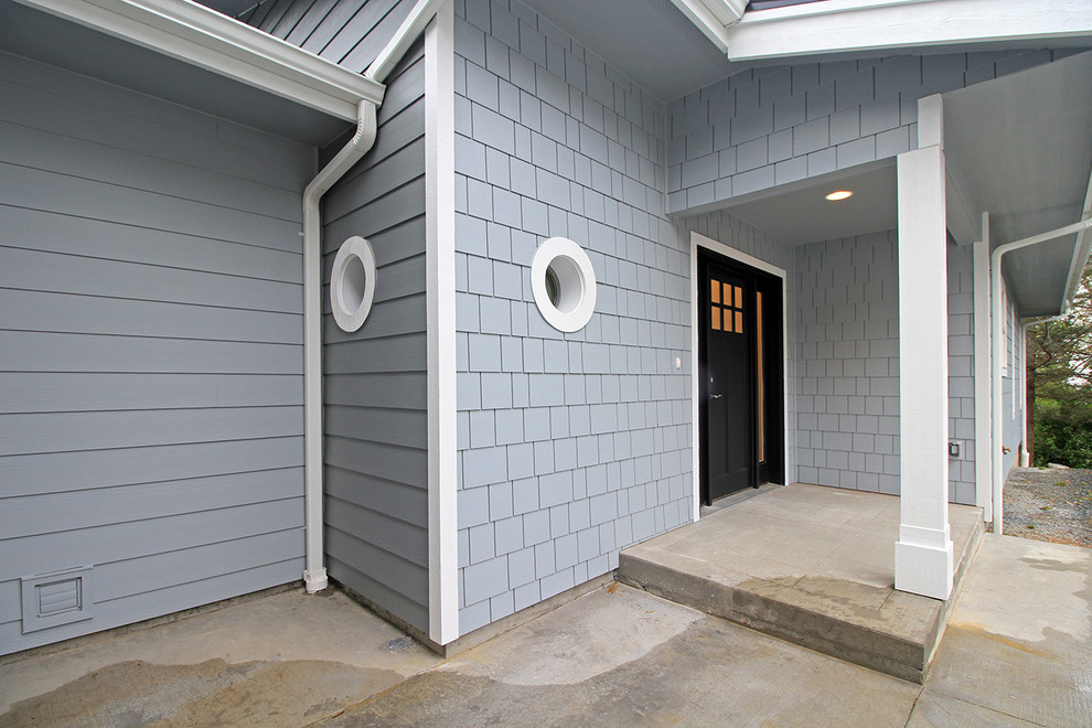 Modelo de puerta principal costera de tamaño medio con paredes azules, suelo de cemento, puerta simple y puerta negra