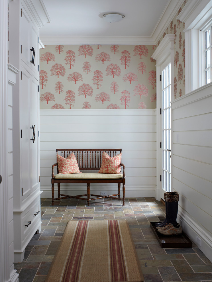 Example of a large ornate slate floor entryway design in New York with white walls and a glass front door