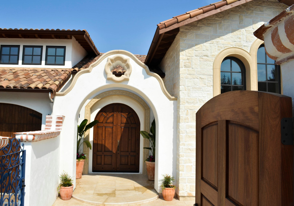 Aménagement d'une porte d'entrée méditerranéenne de taille moyenne avec un mur blanc, un sol en travertin, une porte double, une porte en bois foncé et un sol beige.