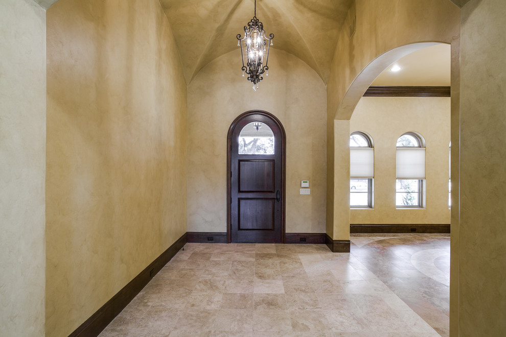 Photo of a large mediterranean foyer in Dallas with beige walls, travertine flooring, a single front door and a dark wood front door.