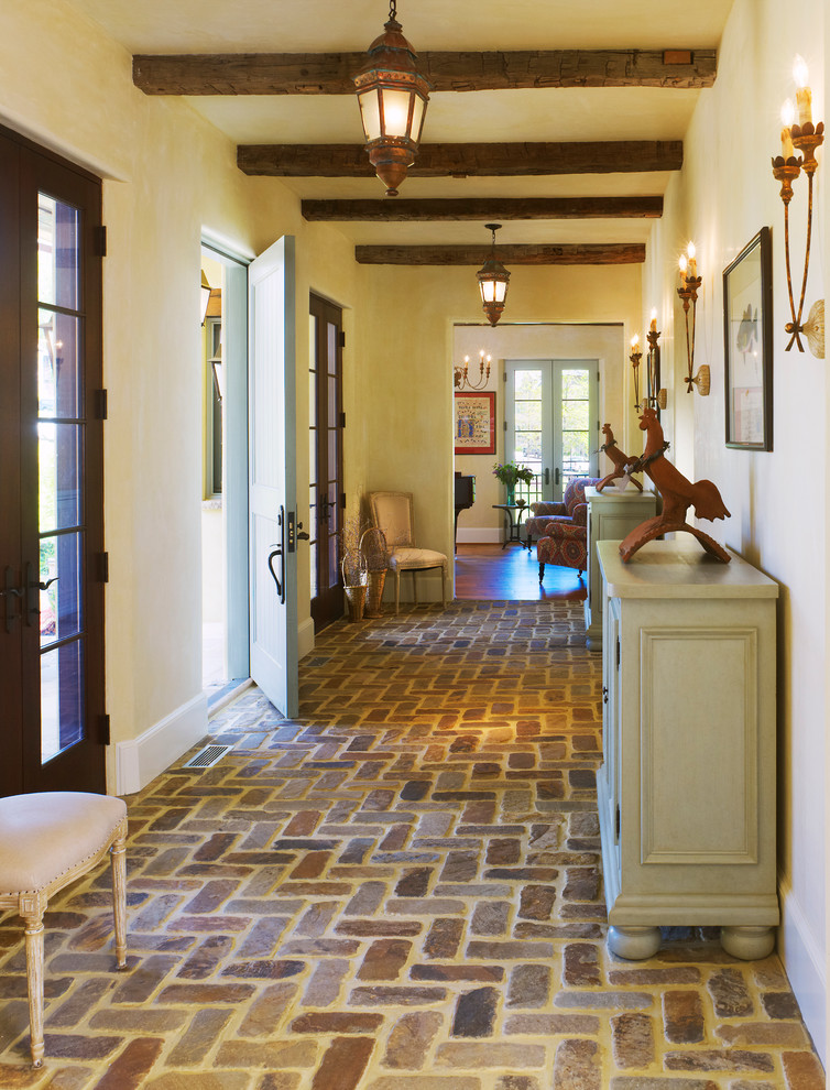 Inspiration for a french country brick floor entryway remodel in DC Metro with yellow walls and a blue front door