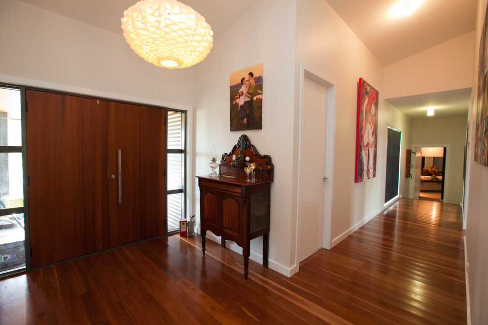 Modernes Foyer mit weißer Wandfarbe, dunklem Holzboden und dunkler Holzhaustür in Canberra - Queanbeyan