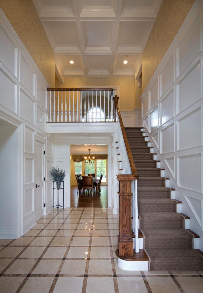 Example of a large classic beige floor and marble floor foyer design in New York with white walls