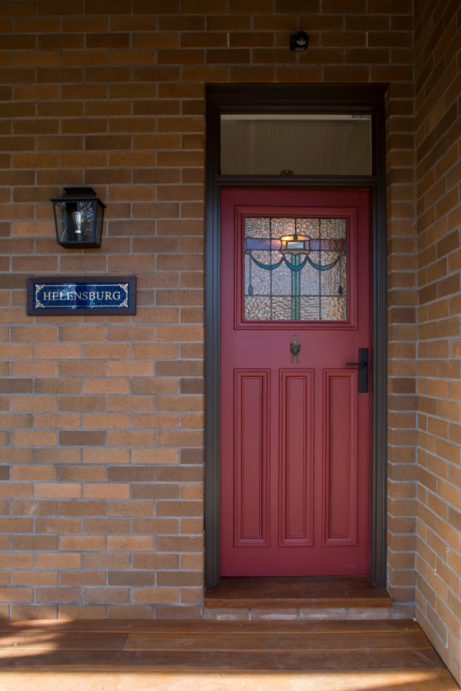 Bild på en mellanstor ingång och ytterdörr, med bruna väggar, mörkt trägolv, en enkeldörr, en röd dörr och brunt golv