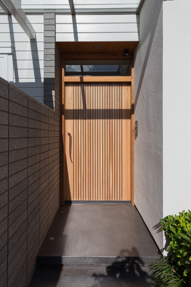 Exemple d'une grande porte d'entrée moderne avec un mur blanc, sol en béton ciré, une porte simple et une porte en bois brun.