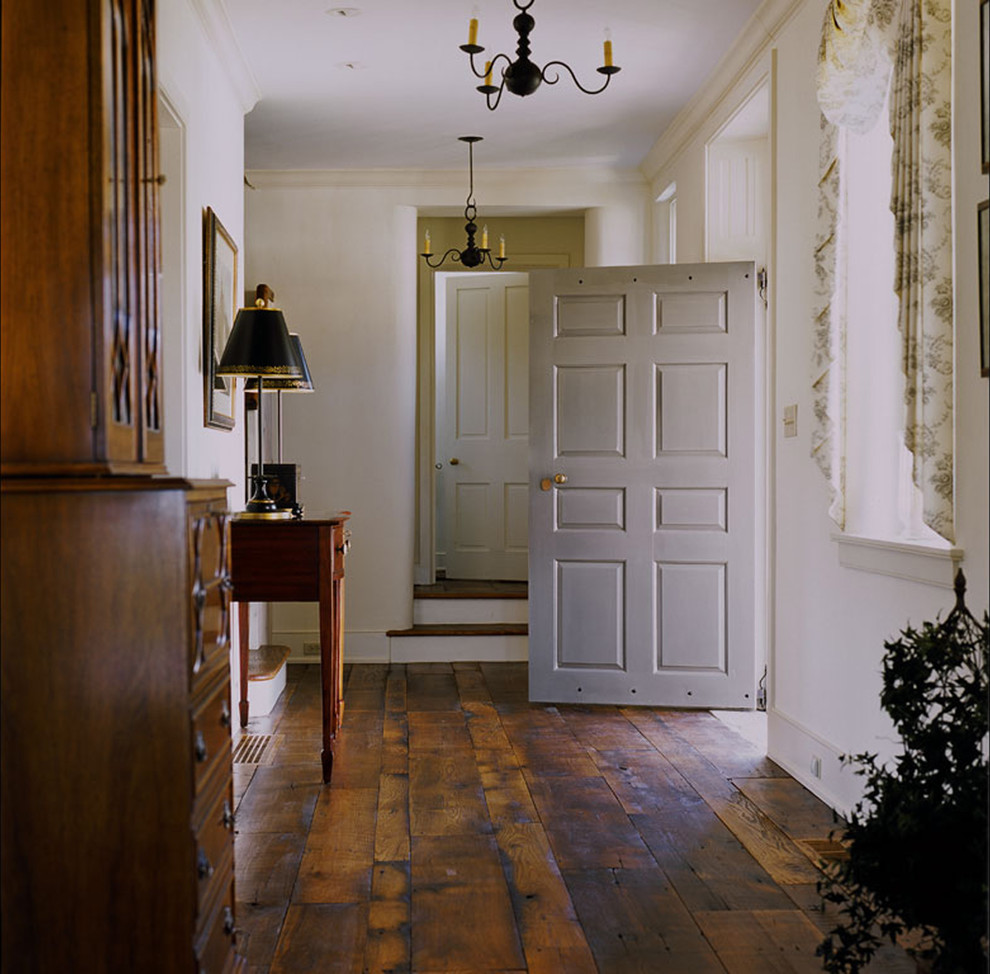 Farmhouse entrance in Philadelphia with beige walls, dark hardwood flooring and feature lighting.