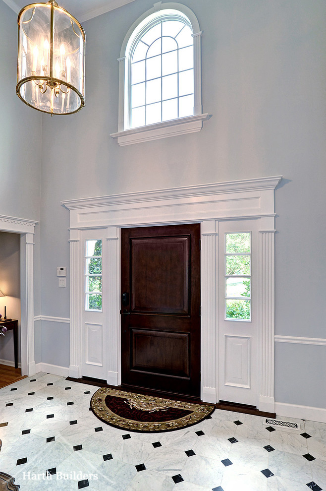 Inspiration pour un grand hall d'entrée traditionnel avec un mur gris, un sol en carrelage de porcelaine, une porte simple et une porte en bois foncé.