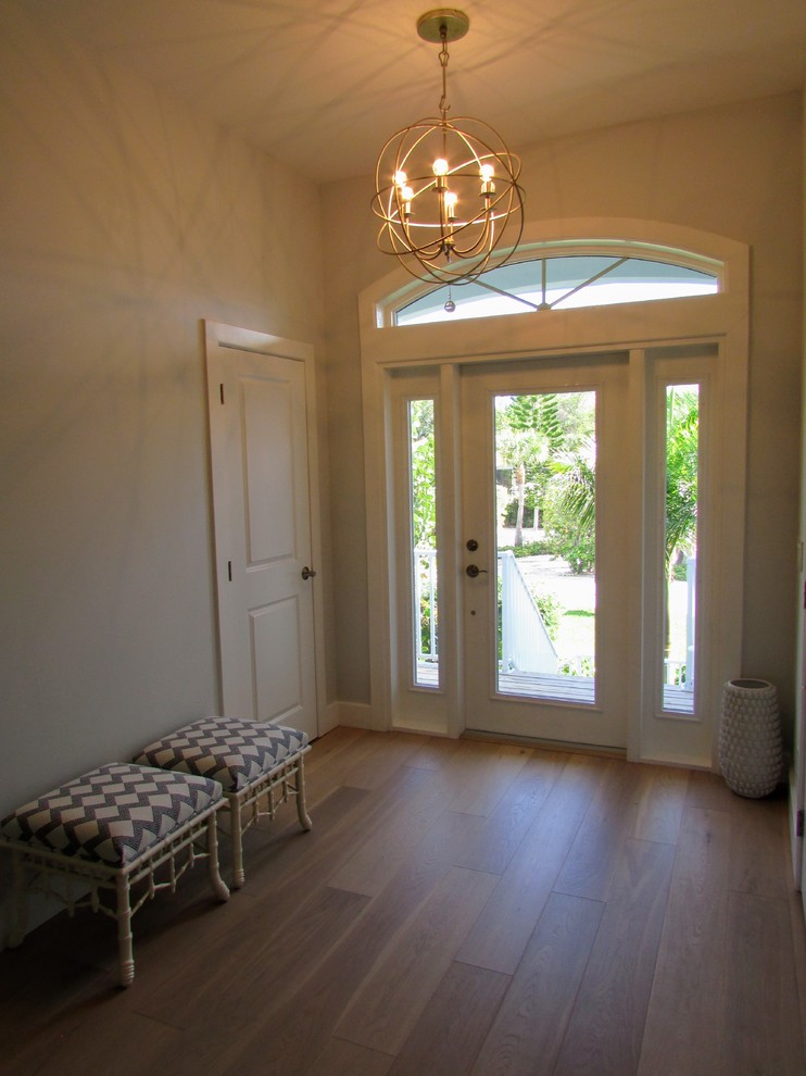 Immagine di una porta d'ingresso chic di medie dimensioni con pareti beige, pavimento in legno massello medio, una porta singola, una porta in vetro e pavimento beige