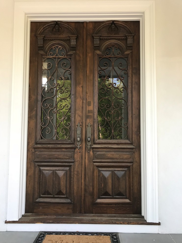 На фото: большая входная дверь в стиле неоклассика (современная классика) с бежевыми стенами, полом из травертина, двустворчатой входной дверью, входной дверью из темного дерева и бежевым полом с